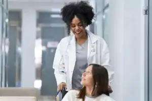 Médica leva paciente em cadeira de rodas pelo corredor do hospital e oferece uma boa experiência do paciente